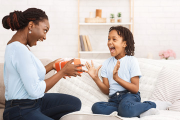 Mother giving birthday present for happy daughter