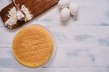 Flour and eggs for cooking sponge cake on white wooden background, copy space
