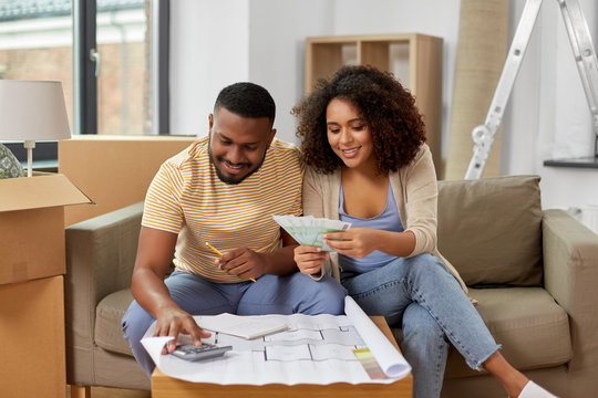 mortgage, moving and real estate concept - happy african american couple with blueprint and calculator counting money for repair costs to new home