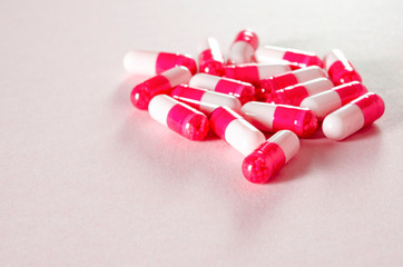 White oval heart-shaped tablets lie on a pink background.