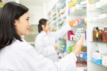 asian female pharmacist check medicine stock in drugstore,she holding drug strip pack , they learning and sharing knowledge together, quality development activity - obrazy, fototapety, plakaty