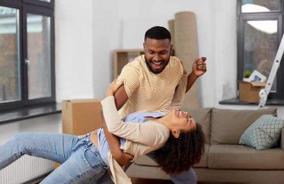 moving, repair and real estate concept - happy african american couple dancing at new home