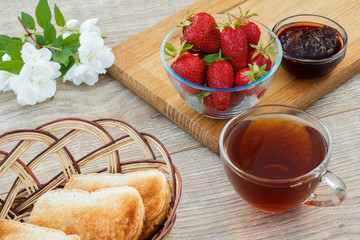 Glass cup of tea, bread, strawberries with white jasmine flowers