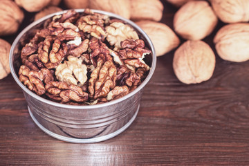 walnuts in the bowl and on the table close-up. peeled walnuts close-up in a metal bowl.