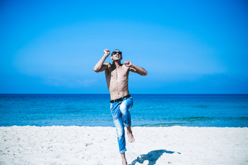 young muscular man resting and posing on the beach. Jump in the air