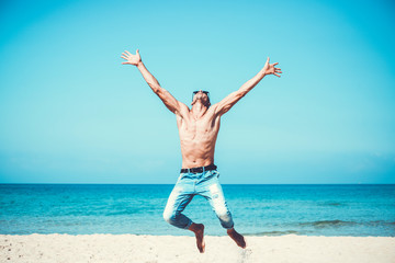 Obraz premium young muscular man resting and posing on the beach. Jump in the air