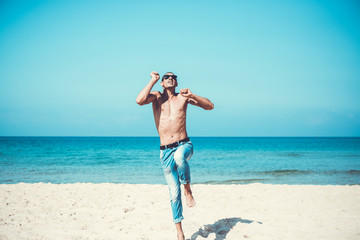 young muscular man resting and posing on the beach. Jump in the air