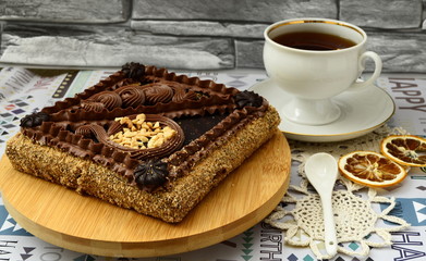 Shortcake with nuts decorated with chocolate cream. Close-up. Cup of tea, a slice of lemon on the table.