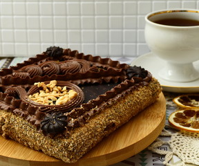 Shortcake with nuts decorated with chocolate cream. Close-up. Cup of tea, a slice of lemon on the table.