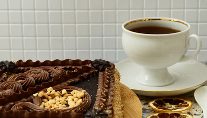 Shortcake with nuts decorated with chocolate cream. Close-up. Cup of tea, a slice of lemon on the table.
