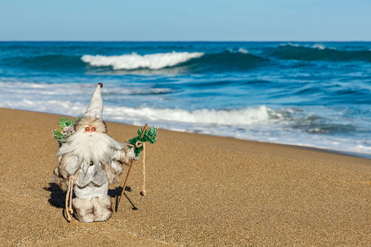 Santa figure on the beach, tropical ocean background, Christmas travel concept, copy space