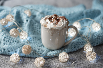 cozy winter composition with cup of hot chocolate, hot cooca cup with knitted sweater and ball lights, girly winter aesthetic photography