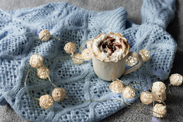 cozy winter composition with cup of hot chocolate, hot cooca cup with knitted sweater and ball lights, girly winter aesthetic photography