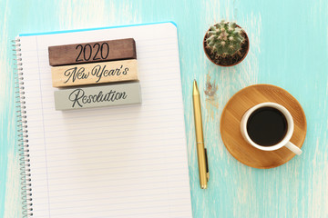 Business concept of top view 2020 year's resolution list with notebook, cup of coffee over blue wooden desk