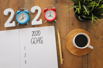 Business concept of top view 2020 goals list with notebook, cup of coffee over wooden desk