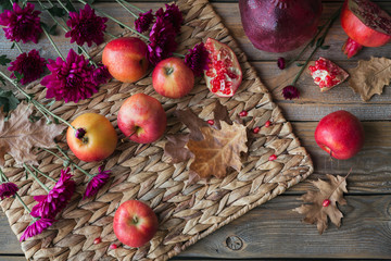 Harvest of red apples, grapefruit with autumn leaves and flowers on a wooden table