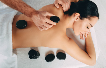 Hot stone treatment at spa resort. Woman while hot stone massage, view from above