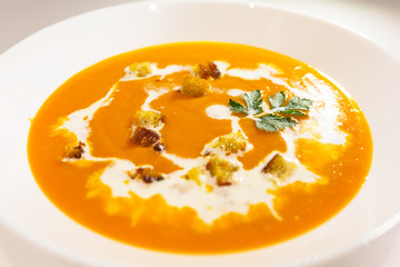 Pumpkin and carrot soup with cream, toasts and parsley