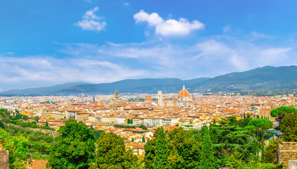 Top aerial panoramic view of Florence city with Duomo Cattedrale di Santa Maria del Fiore cathedral, buildings houses with orange red tiled roofs and hills range, blue sky white clouds, Tuscany, Italy