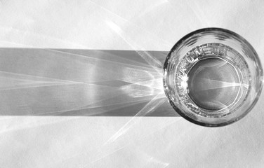 Water glass with strong shadows on white background