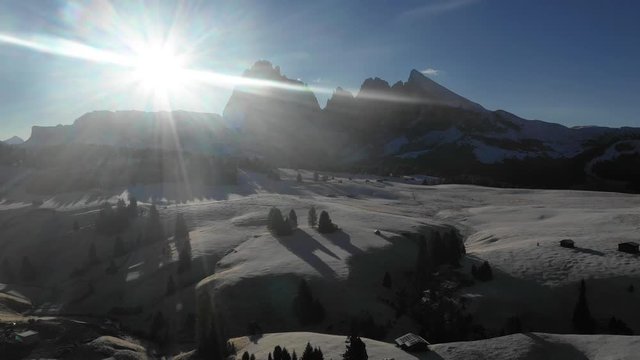 Aerial view of mountains with snow at sunrise - Backlight panoramic video of Dolomites in winter with snow on the valley - Nature and travel concepts