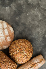Crusty bread, several different loaves of bread on black background. Top view, flat lay, copy space.