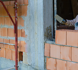 Detail of construction site, trowel or putty knife on top of brick layer