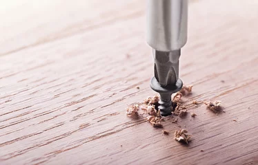 Fotobehang screwdriver screw in a wood oaks plank © evkaz