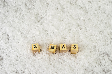 x mas word made of letters on wooden cubes on a snow background