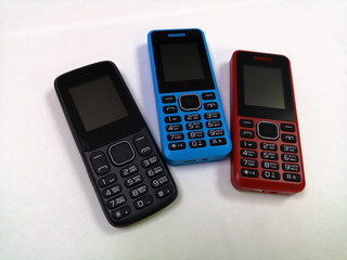 Mobile phones with buttons of different colors lie on a white background
