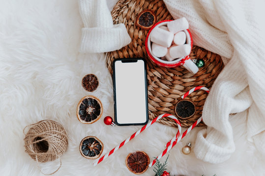 Smartphone with empty screen and Christmas decorations. Flat lay Holiday composition with marshmallow, Christmas Mock Up