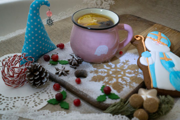 Still life with a glass of mulled wine or fruit tea with lemon slice with gingerbread on a wooden board and linen tablecloth Christmas and Christmas table setting. Greeting card.