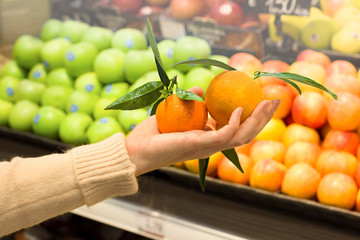 Female hand choosing tagerines in supermarket. Concept of healthy food, bio, vegetarian, diet.