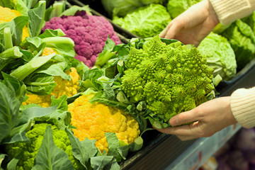 Female hand choosing roman cauliflower in the store. Concept of healthy food, bio, vegetarian, diet.