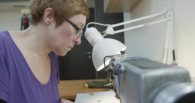 Woman seamstress working on an industrial sewing machine. Close-up of the sewing process.