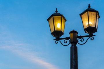 Fototapeta na wymiar The yellow light of the street lamp has a beautiful blue sky background
