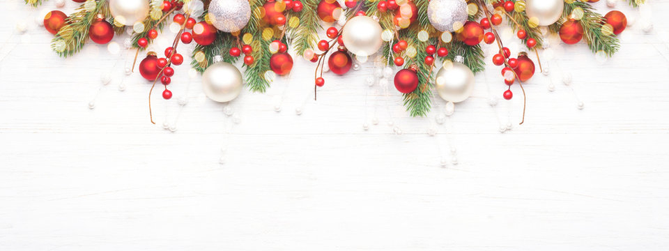 Classic Christmas composition with fir branches and white and red baubles on white wooden background. Noel banner for website.