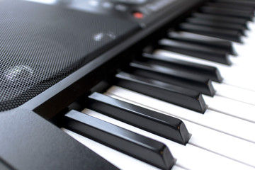 Close up photo of classic electronic digital musical midi piano keyboard or two octaves modern synthesizer and speakers. Music instrument, player concept. Black and white key. Home record music studio