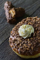 donut with cream and chocolate bar on wooden table