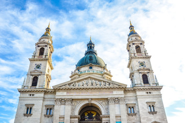 Fototapeta premium Front facade of St. Stephen's Basilica in Budapest, Hungary on with blue sky and clouds above. Roman Catholic basilica built in neoclassical style. Two towers and cupola of the religious building