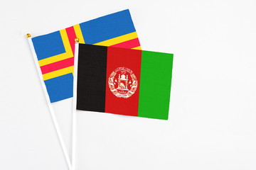 Afghanistan and Aland Islands stick flags on white background. High quality fabric, miniature national flag. Peaceful global concept.White floor for copy space.