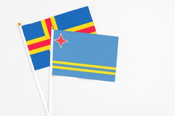 Aruba and Aland Islands stick flags on white background. High quality fabric, miniature national flag. Peaceful global concept.White floor for copy space.