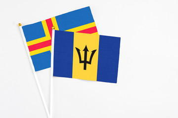 Barbados and Aland Islands stick flags on white background. High quality fabric, miniature national flag. Peaceful global concept.White floor for copy space.