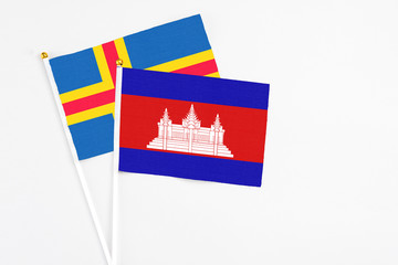Cambodia and Aland Islands stick flags on white background. High quality fabric, miniature national flag. Peaceful global concept.White floor for copy space.