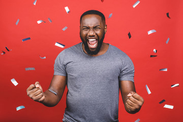 Cheerful african american young man dancing over red background. Winner celebrates. Great success....