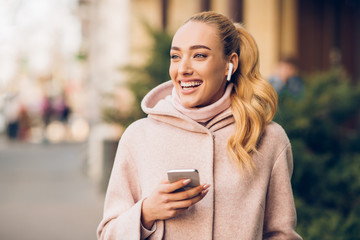 Happy woman walking in city and listening music