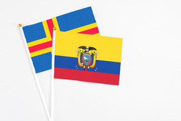 Ecuador and Aland Islands stick flags on white background. High quality fabric, miniature national flag. Peaceful global concept.White floor for copy space.