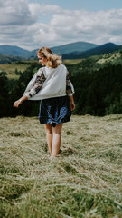 Happy Woman standing on the mountain top looking at panoramic view of mountain range under blue sky