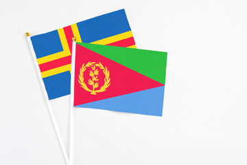 Eritrea and Aland Islands stick flags on white background. High quality fabric, miniature national flag. Peaceful global concept.White floor for copy space.