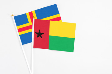 Guinea Bissau and Aland Islands stick flags on white background. High quality fabric, miniature national flag. Peaceful global concept.White floor for copy space.